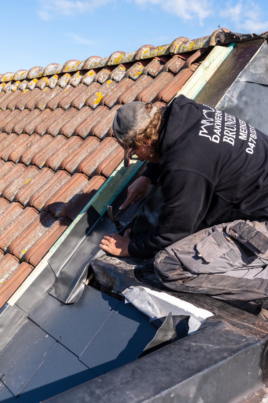 Dakwerker van Dakwerken Bruneel werkt het lood- en zinkwerk af tussen de dakpannen