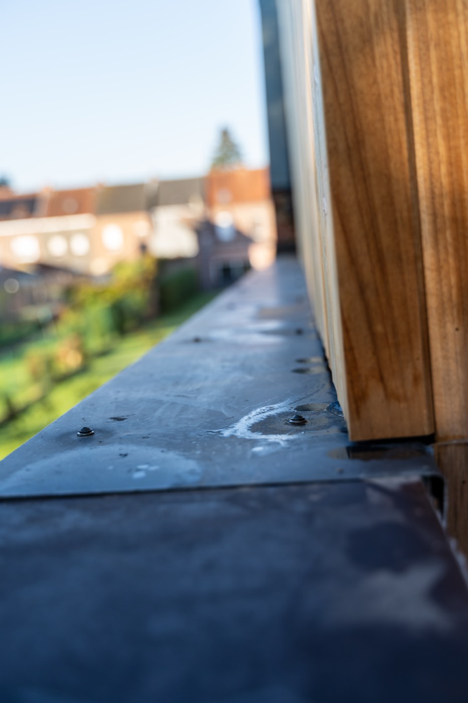 Detail van een zinken dakrand met loodwerk langs een houten dakconstructie